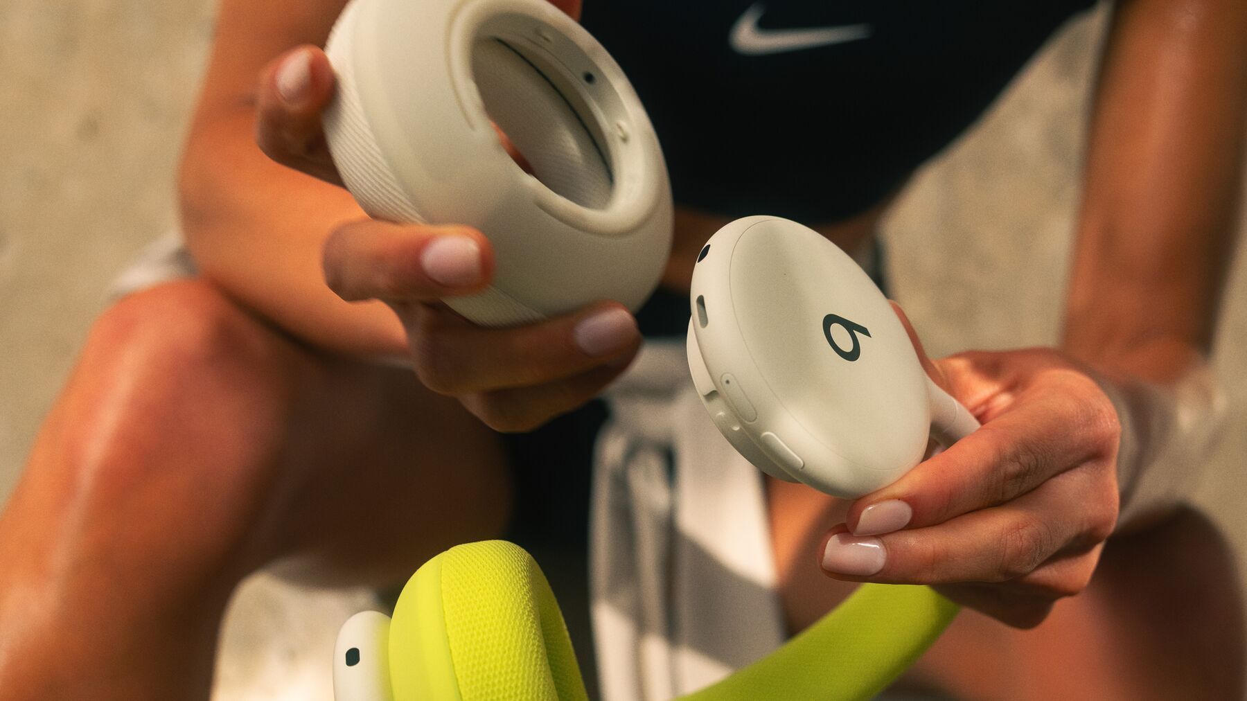 Deux mains retirant un coussinet magnétique de l’oreillette d’un casque Beats 360 ivoire