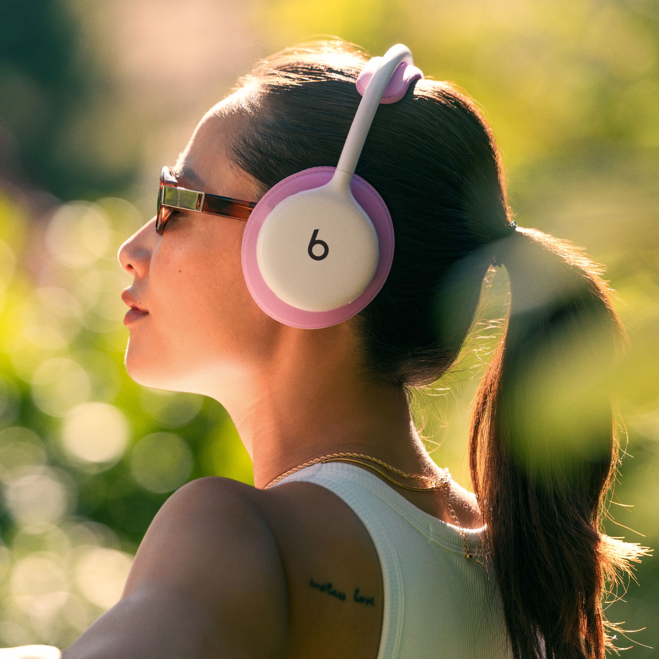 Personne portant un casque Beats 360 rose en extérieur, à contre-jour