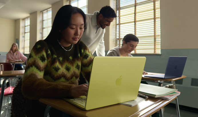 Une étudiante utilise un MacBook Neo, couleur jaune agrume, débranché, dans une salle de classe